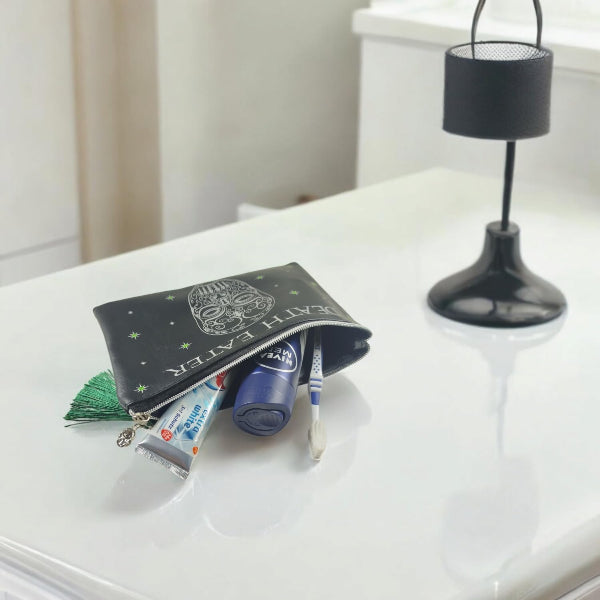 Black pouch with cosmetic items on a white surface