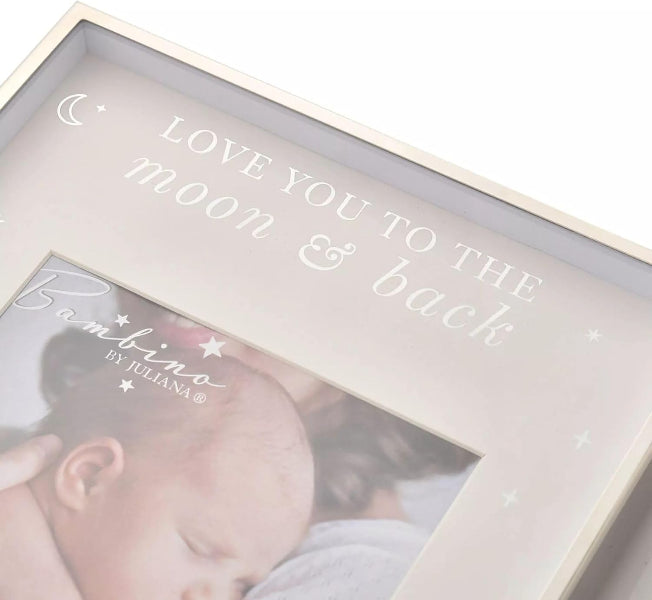 A close-up of a personalized baby photo frame with a cream-colored wooden border and a clear top. The inside features a light blush pink background with white printed text reading 'LOVE YOU TO THE moon & back' and 'Bambino BY JHILANA' over a photo of a sleeping newborn baby.