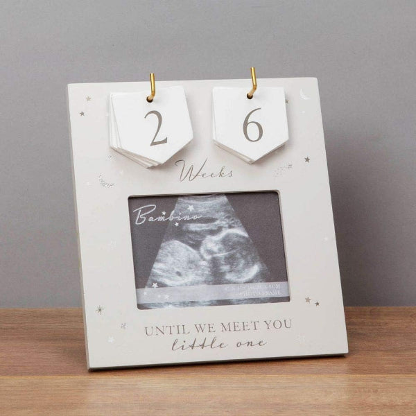 Baby countdown frame with ultrasound photo on a wooden surface and gray background