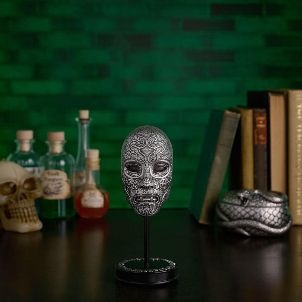 Decorative skull mask on a stand with bottles and books in the background