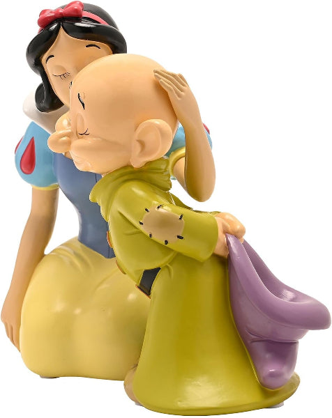 A collectible figurine of Snow White and the Seven Dwarves in a tender embrace, featuring Snow White in her classic blue and yellow dress with a red bow, and the dwarves in their green outfits, set against a plain white background.