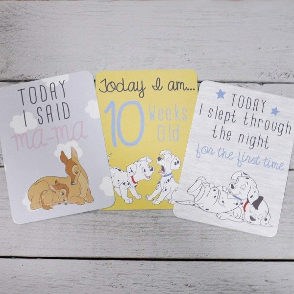 Three milestone cards for a baby's first year on a wooden surface