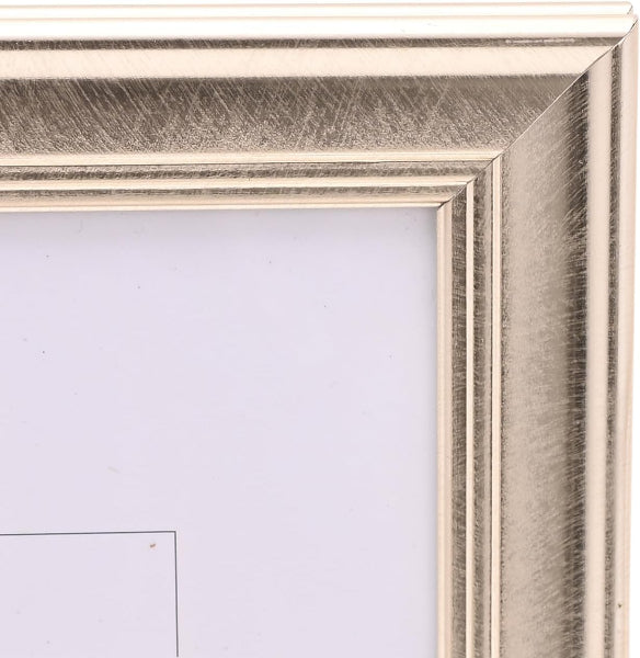 Close-up of a picture frame corner showing a textured metallic silver frame with a light-colored mat or insert.