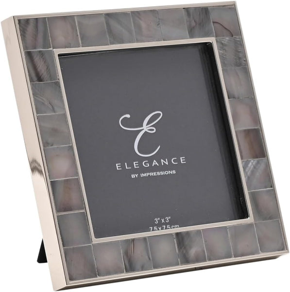 A 3x3 inch picture frame with a polished silver-tone metal frame and a border of rectangular mother-of-pearl tiles in gray, beige, and white tones. The center insert displays the brand logo 'ELEGANCE BY IMPRESSIONS'.