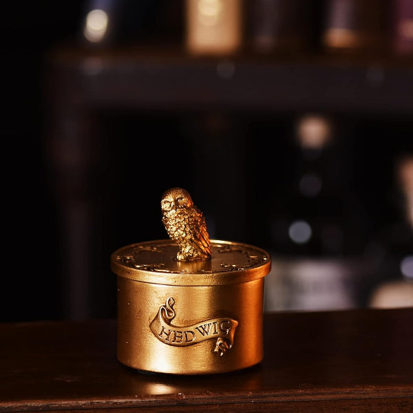 Bronze owl figurine on a circular base with 'Hedwig' engraved, against a blurred background.