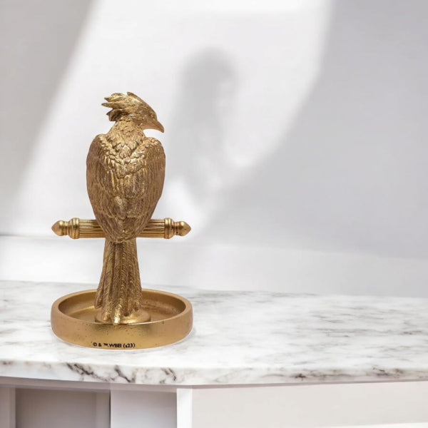 Gold eagle-shaped object on a marble surface with a white background