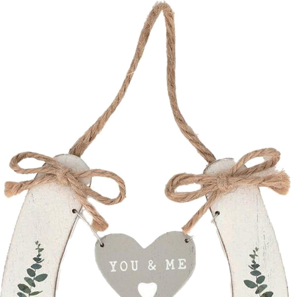Decorative hanging heart with 'YOU & ME' text and eucalyptus designs on a white background.