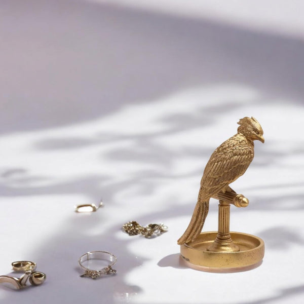 Gold bird-shaped jewelry stand with rings on a light surface