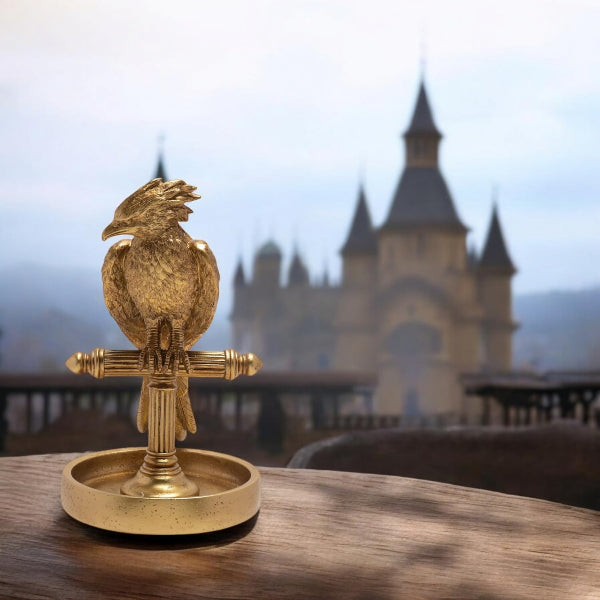 Gold bird-shaped object on a stand with a castle in the background