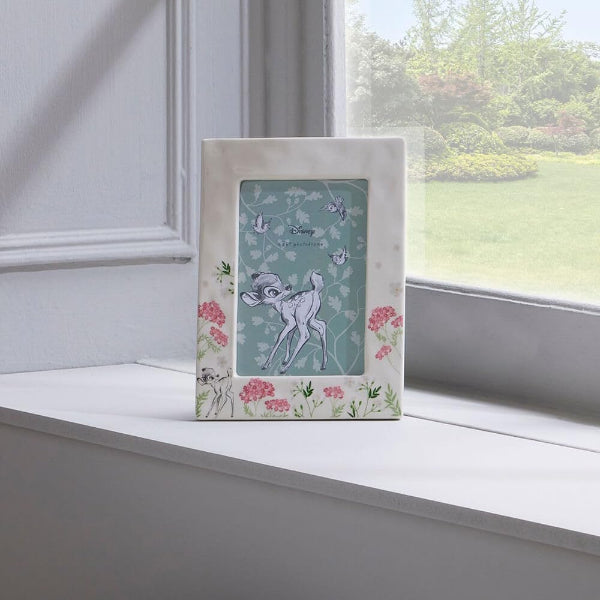 Decorative photo frame with a cartoon deer design on a windowsill.