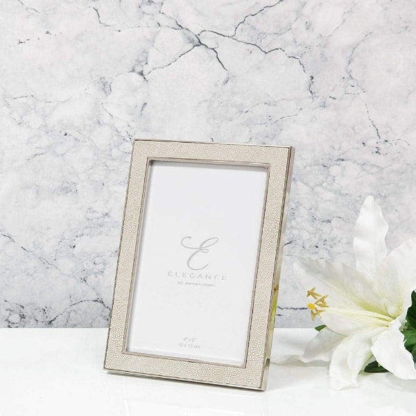Silver photo frame on a marble surface with a white flower