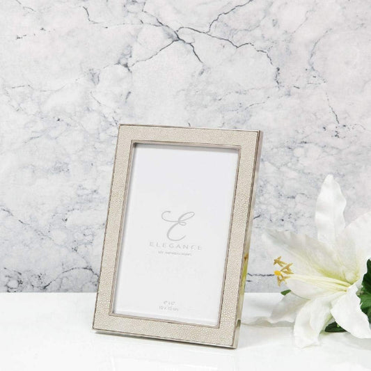 Silver photo frame on a marble surface with a white flower