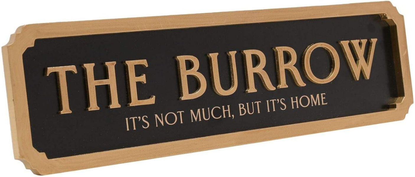 A rectangular wooden sign with a black face and raised gold lettering that reads “THE BURROW” with the smaller phrase “IT’S NOT MUCH, BUT IT’S HOME” below, shown on a plain white background.