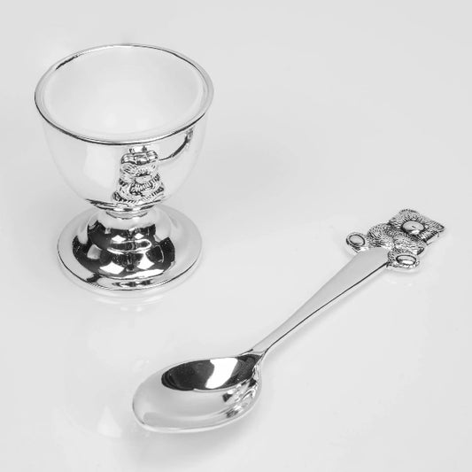 Silver goblet and spoon with decorative handles on a white background