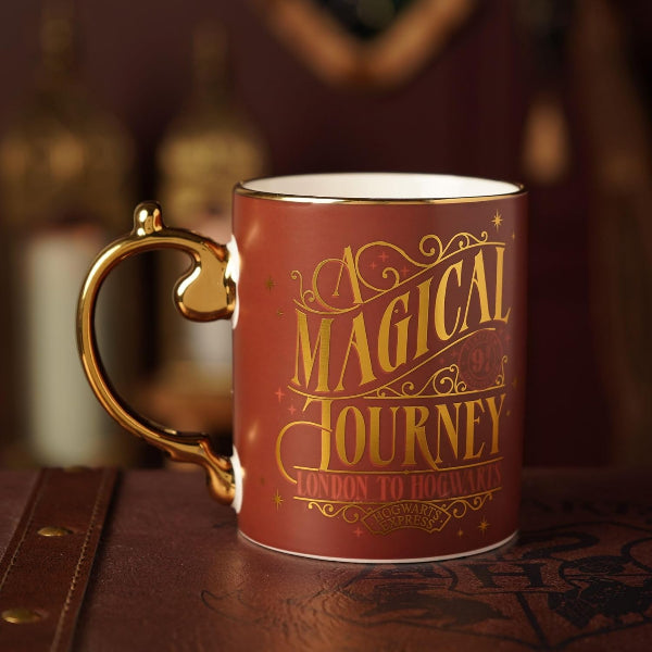 Red mug with gold text 'A Magical Journey' on a wooden surface.