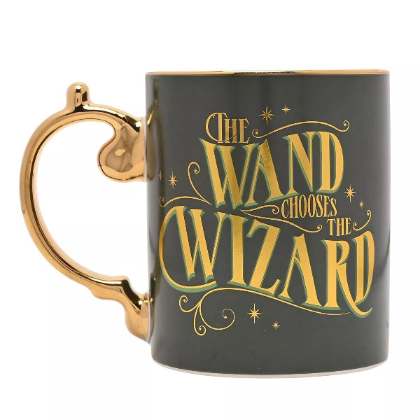 Black mug with gold handle and 'The Wand Chooses the Wizard' text on a white background
