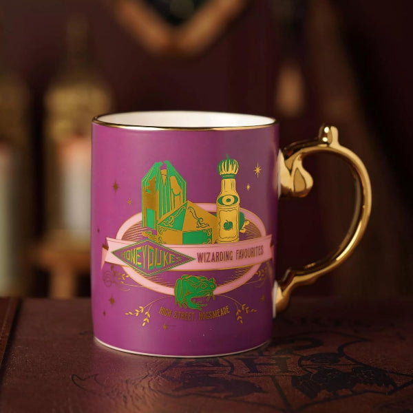 A purple ceramic mug with a gold handle and gold rim, featuring a Hogwarts-themed graphic with the text 'ONE DUKE WIZARDING FAVOURITE' and 'HOGWARTS FAN MADE'.