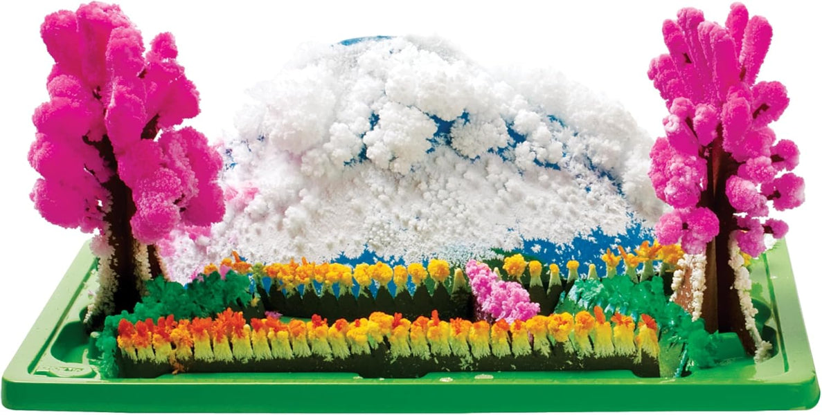 Model of a landscape with pink trees, snow, and colorful flowers on a green base.