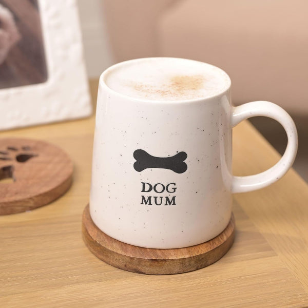 White mug with 'DOG MUM' text and bone symbol on a wooden coaster