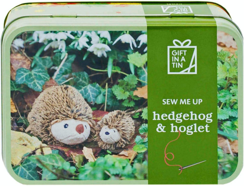 Gift-in-a-tin with hedgehog and hoglet toys and sewing kit on a green background
