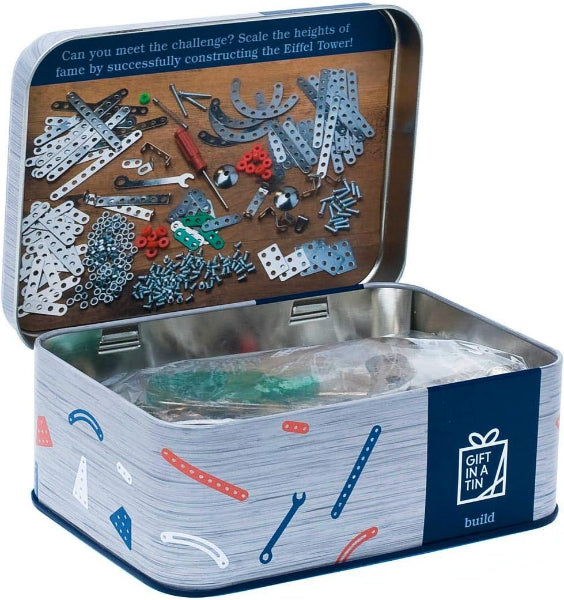 Open tin containing building block components with a wooden base and blue label.