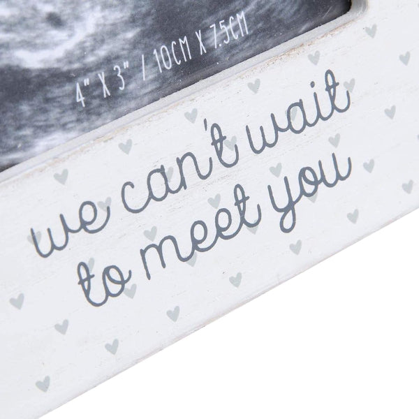 Ultrasound image with a card that says 'we can't wait to meet you' on a white background.