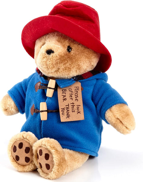 Plush toy bear wearing a red hat and blue coat with a tag on a white background