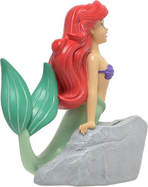 Mermaid figurine with red hair and green tail on a gray rock against a white background