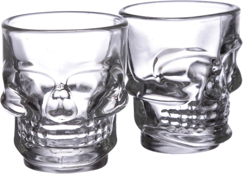 Two clear glass skull-shaped shot glasses on a white background