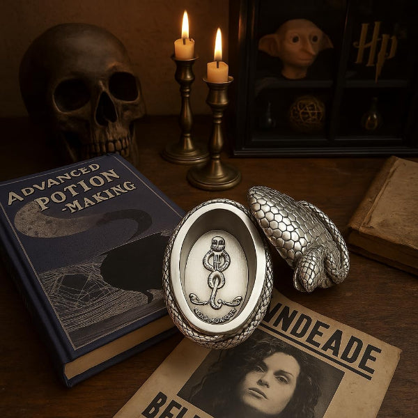 Silver potion container with snake emblem on a table with books and candles