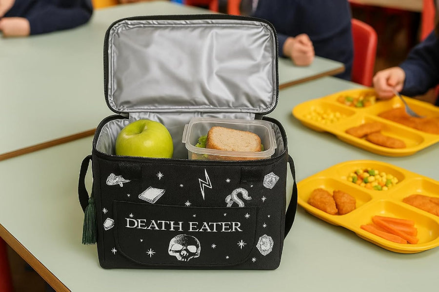 Black 'Death Eater' lunch bag with food items on a school cafeteria table.