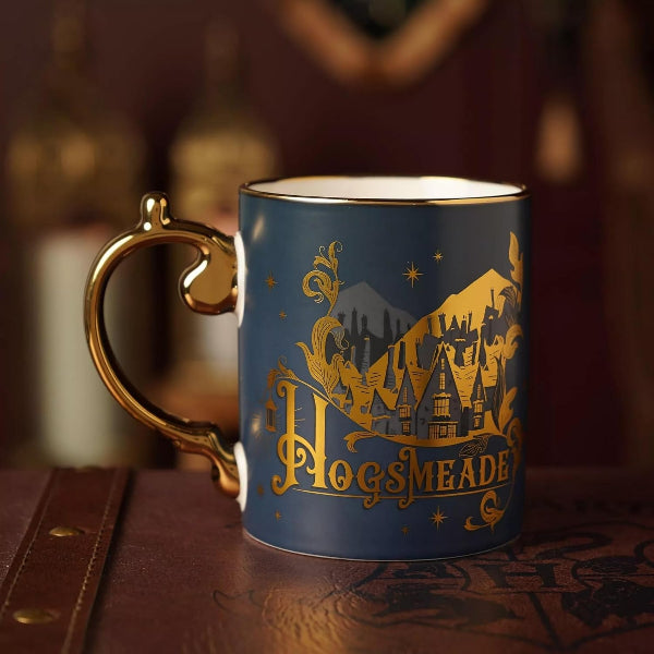 Blue mug with gold handle and 'Hogwarts' design on a wooden surface