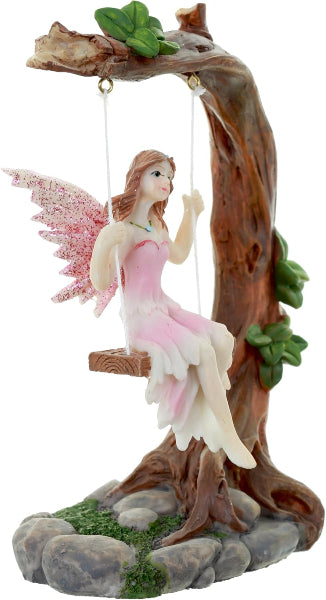 Fairy figurine on a swing with pink wings and a pink dress, sitting on a tree branch.
