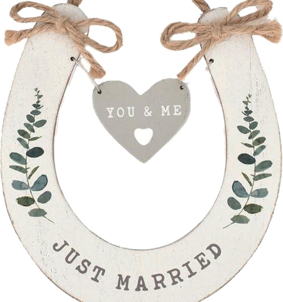 Decorative wooden horseshoe with 'You & Me' heart and 'Just Married' text, tied with twine.