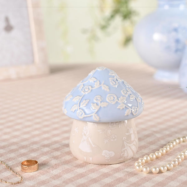 Decorative mushroom-shaped container with floral design on a textured surface.