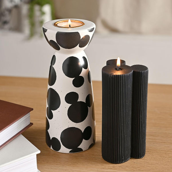 Ceramic candle holder with black and white polka dot design on a wooden surface.