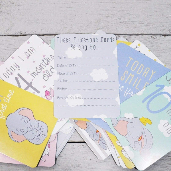 Set of milestone cards with baby illustrations on a wooden surface