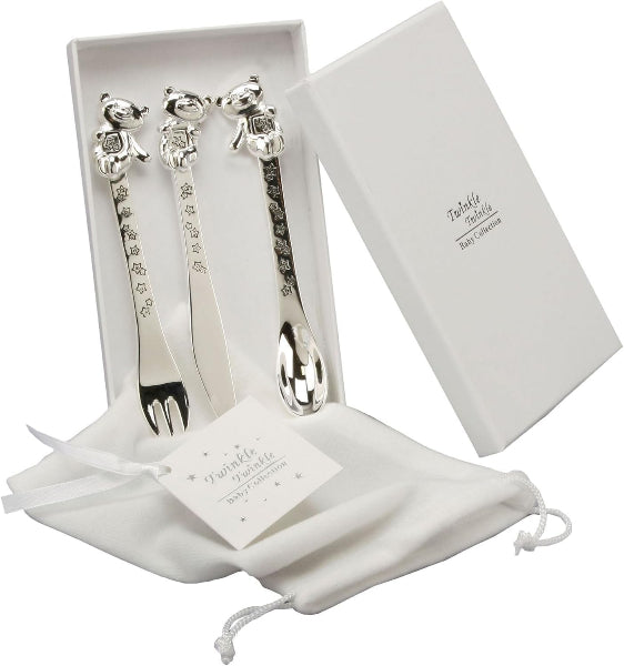 Set of silver baby utensils with a white box and drawstring bag on a white background
