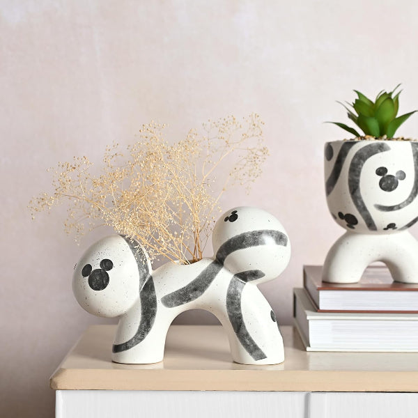 Decorative ceramic dog figurines with black patterns on a table against a light pink wall.