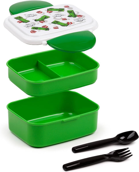 Green bento box with compartments and black utensils on a white background