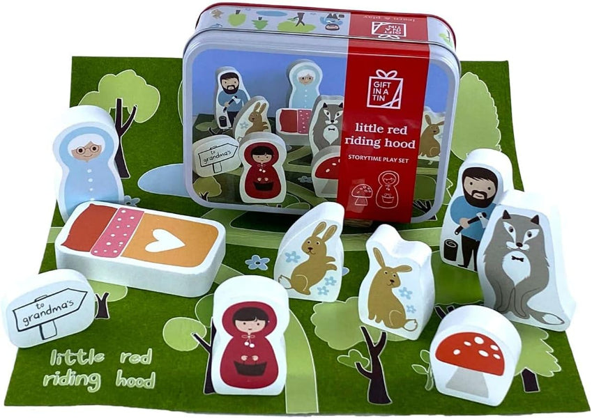 Little Red Riding Hood wooden storytelling play set with a red tin box, illustrated game board, and multiple wooden character pieces including Little Red Riding Hood, grandmother, wolf, rabbit, and bear on a green printed background.