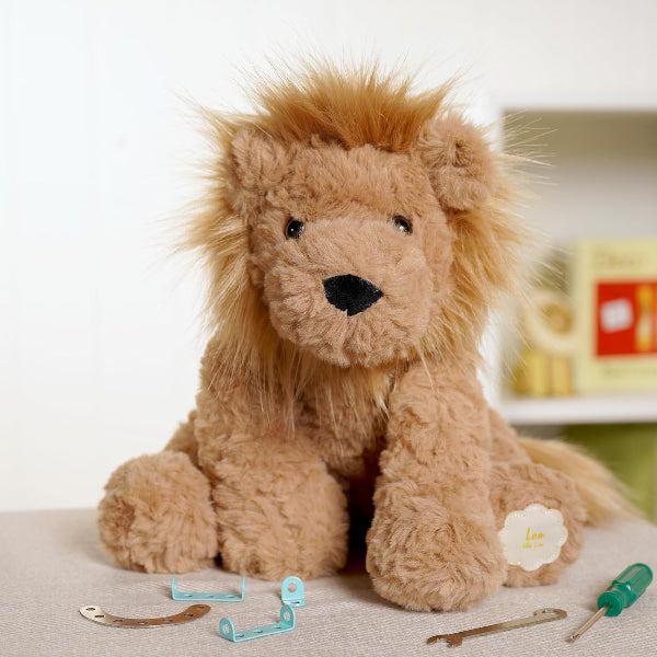 Plush lion toy with tools on a light surface