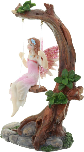 Fairy figurine on a swing made of wood and leaves with a white background.