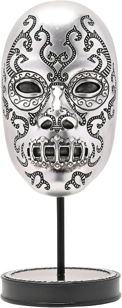 Decorative skull mask with intricate designs on a stand against a white background