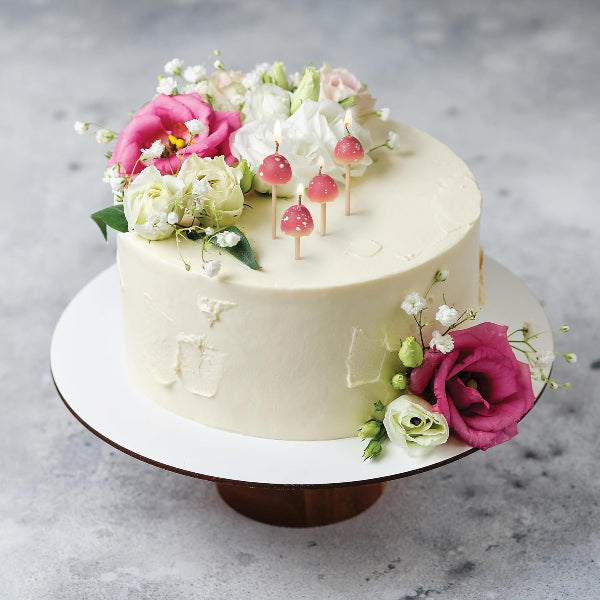 Decorative cake with flowers and candles on a gray surface