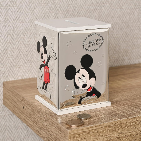 Mickey Mouse-themed money box on a wooden surface with coins around it.