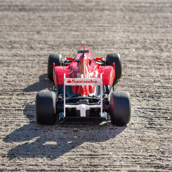 Red Formula 1 car on a dirt track with 'Santander' branding.