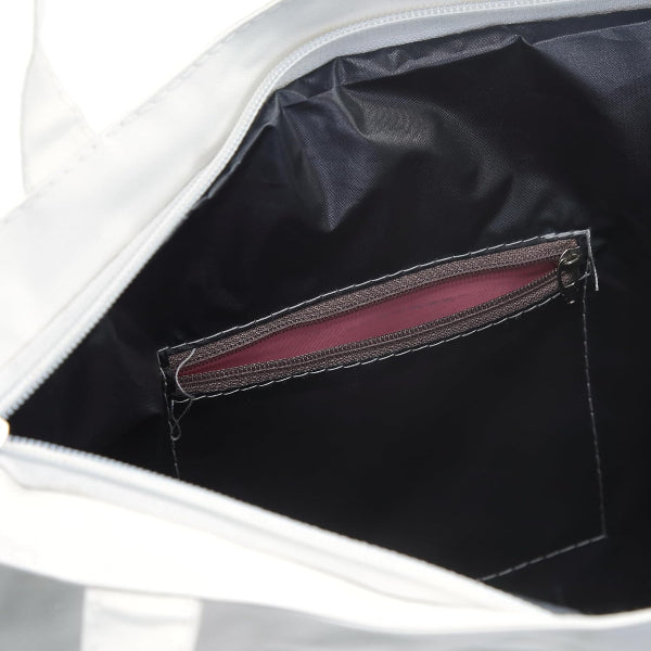 Close-up of a white bag with a black interior pocket and red lining.