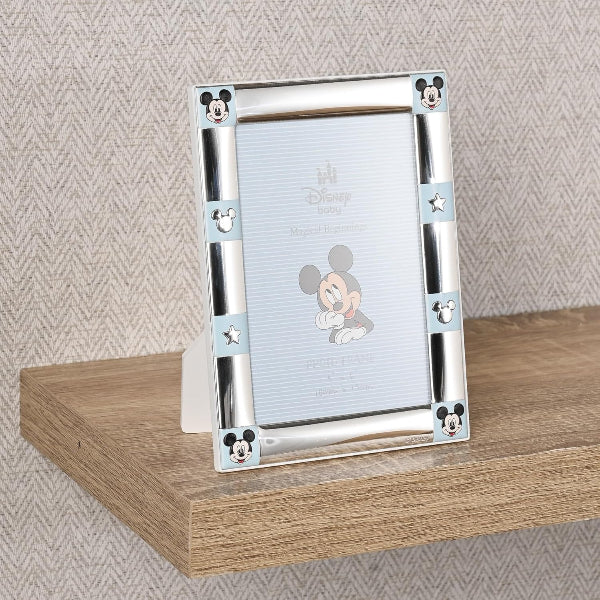 Silver photo frame with Disney character design on a wooden surface and patterned wall background