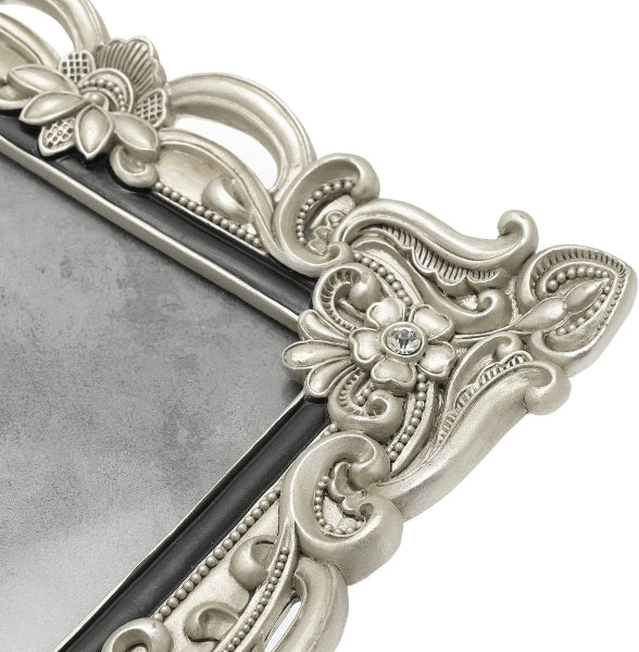 Decorative silver mirror with intricate floral and scroll designs on a white background